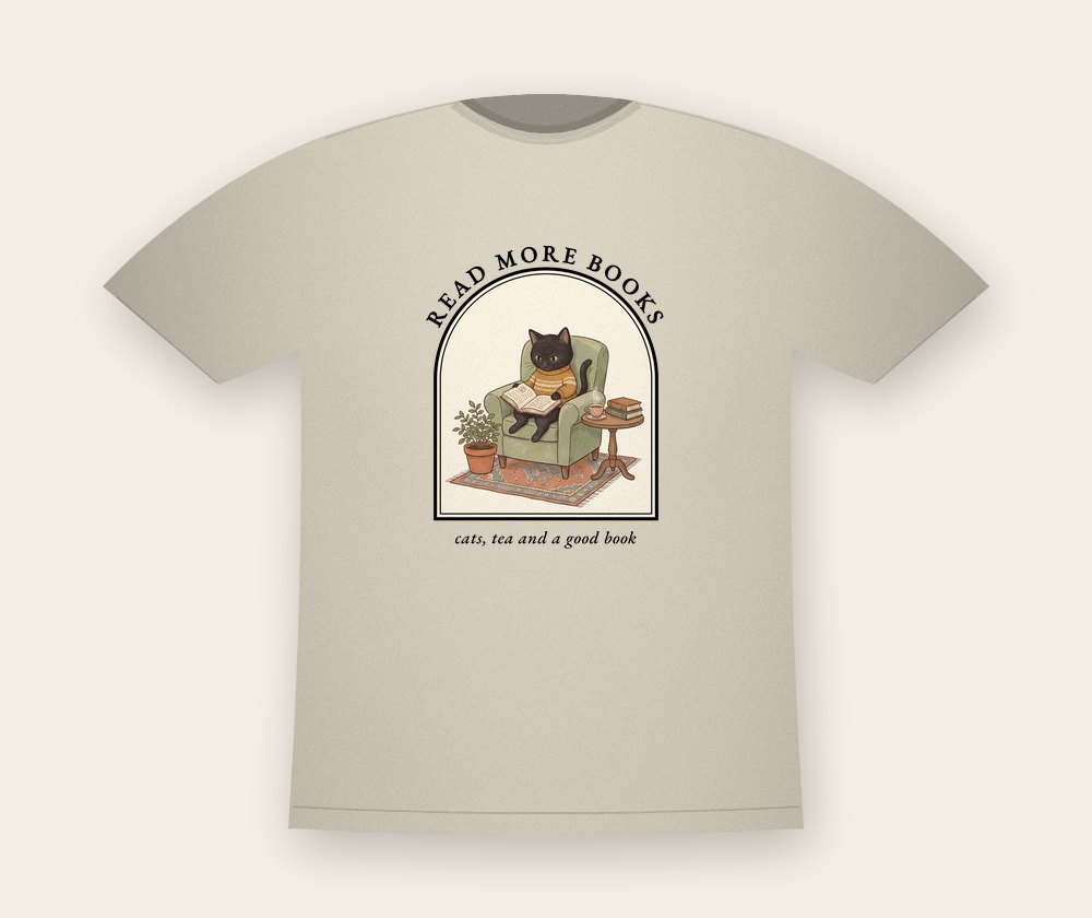 Sand T-shirt with a black cat reading in a green armchair inside an arched window, with the text Read more books