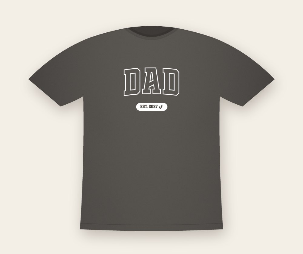 Washed grey T-shirt with the word DAD in outlined varsity letters and a small label EST. 2027 with baby footprints